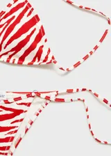 Braga de bikini estilo brasileña con estampado de cebra en rojo y blanco, anillas metálicas decorativas y cierre de lazos laterales.