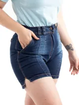 Bermuda de jean azul oscuro con cintura alta, trabillas, cierre con botón y cremallera, bolsillos delanteros y traseros, y aberturas laterales en el ruedo.