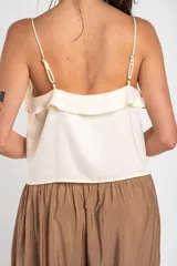 Musculosa negra de satén con escote en V, tirantes finos y detalle de volados en el pecho.