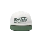 Gorra Eme Studios modelo Lister Turf Cap, color blanco con visera plana en verde oscuro. Cuenta con bordado frontal en relieve con texto en color verde.