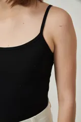 Musculosa de bretel fino color crudo, corte ajustado al cuerpo y escote redondo.