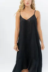 Vestido negro midi con tirantes finos y escote en V. Diseño fluido con bajo asimétrico.