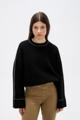 Sweater negro de corte holgado con cuello redondo a la base y detalle de costuras decorativas en contraste a lo largo de las mangas y el cuello.