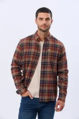 Camisa de viyela de manga larga con estampado de cuadros en tonos marrones, azules y beige. Presenta cuello clásico con botones, cierre frontal abotonado y un bolsillo en el pecho.