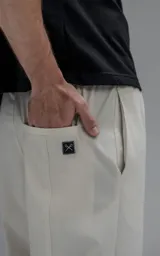 Pantalón de corte oversize confeccionado en microfibra técnica con sutil elasticidad. Presenta cintura elástica, bolsillos laterales y un bolsillo cargo con cierre de broche snap. Incluye un sistema de elásticos con tancas en los tobillos para regular la apertura y modificar la silueta.