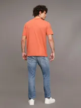 Remera color naranja de corte clásico y manga corta. Tiene cuello redondo y una insignia con el monograma de Calvin Klein en la manga.