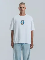 Remera blanca de manga corta con cuello redondo y calce oversize. Presenta un estampado frontal de Mickey Mouse vestido de chef.