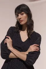 Vestido corto negro de broderie de algodón, con escote en V, mangas tres cuartos, cintura elastizada, falda corte A con volado y forro interior.