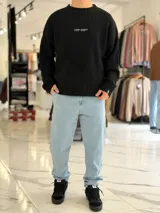 Sweater de punto color marrón, de manga larga, con textura acanalada y texto bordado en la espalda.