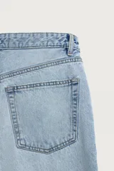 Pantalón jeans de corte recto y ajuste holgado, confeccionado en denim de algodón rígido. Presenta diseño clásico de cinco bolsillos, cierre frontal con cremallera y botón, con un acabado de lavado claro.