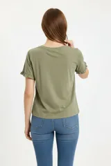 Remera blanca de algodón, de corte ajustado, con cuello redondo y mangas cortas terminadas con volados delicados.