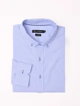Camisa de manga larga marca Cuatro Ases, confeccionada en algodón con diseño de microcuadros en tono azul claro. Presenta cuello clásico con botones, cierre frontal abotonado y bolsillo en el pecho.