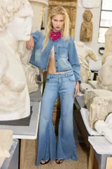 Pantalón jean de corte flare y tiro medio, color celeste con efecto lavado, de diseño amplio en la parte inferior y dobladillo deshilachado.