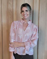 Blusa de algodón color azul, de corte suelto, con mangas largas abullonadas y cuello con volados y escote en V.