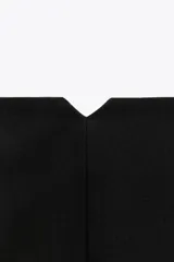 Pantalón blanco de vestir, de tiro alto y corte recto. Presenta bolsillos delanteros de vivo y cierre frontal con cremallera, botón interior y gancho metálico.