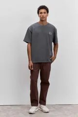 Remera de corte holgado en color gris oscuro con efecto lavado, cuello redondo y pequeño estampado gráfico en el pecho.