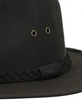 Sombrero tipo fedora de canvas engrasado color verde oscuro, con detalle de cinta trenzada en la base de la copa y ojales metálicos laterales para ventilación.