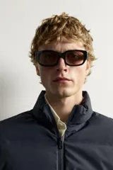 Cazadora acolchada color azul marino, con cuello subido, cierre frontal de cremallera y bolsillos de vivo en la cadera. Las mangas son de tejido liso elástico.
