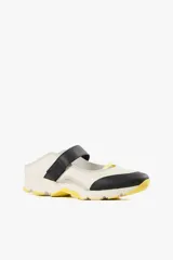 Zapato de diseño urbano color blanco con detalles en negro y amarillo, suela dentada y tira de velcro en el empeine.