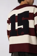 Remera tejida de manga corta con diseño de rayas horizontales anchas en color bordó y crema, de corte relajado y cuello redondo.