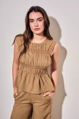 Blusa sin mangas de viscosa con estampado a cuadros vichy en tonos marrones y tostados, con doble fruncido elástico en el pecho y la cintura que genera un sutil vuelo inferior.