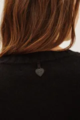 Sweater de punto color negro, con cuello redondo y mangas largas con puños acanalados.