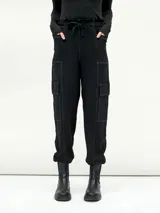 Pantalón negro de corte holgado con cintura elástica ajustable con cordón, bolsillos laterales y bolsillos tipo cargo en los laterales de las piernas.