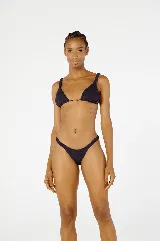 Conjunto de bikini negro con corpiño triangular con tirantes anchos y detalle de argolla dorada en el centro, y bombacha cavada con laterales fruncidos.