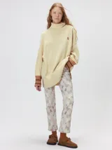 Pullover de punto color rojo, con cuello tortuga, corte holgado y mangas largas con puños acanalados en contraste con rayas blancas. Presenta un logo bordado en el pecho.