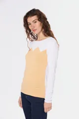 Buzo de tejido de punto con diseño bicolor, combinando blanco en la parte superior y mangas con un tono celeste grisáceo en el cuerpo, presentando un patrón geométrico en la unión de los colores. Posee cuello redondo y mangas largas.