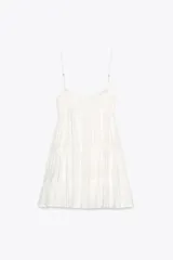 Vestido corto negro de gasa con escote recto y tirantes finos ajustables. El corpiño tiene fruncido elástico y el ruedo es escalonado con volados. Presenta un detalle de encaje a tono en el borde del escote.