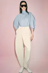 Pantalón de tiro medio confeccionado en algodón, con diseño cruzado en la cintura y cierre frontal con botones. Presenta trabillas para cinturón, bolsillos laterales ocultos y un bolsillo frontal con solapa y botón.