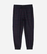 Pantalón de pijama tipo jogger para hombre, confeccionado en tejido plush suave y abrigado. Presenta un diseño estampado a cuadros, cintura elástica con cordón de ajuste y puños elásticos en los tobillos.