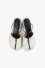 Mules de cuero color blanco con diseño moderno, taco ancho y plataforma. Cuenta con una tira superior negra que aporta estabilidad y un calce cómodo.