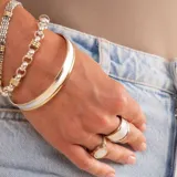 Anillo ancho de diseño moderno, con cuerpo central satinado en plata y bordes pulidos en oro. Presenta una estructura robusta y elegante.