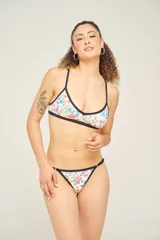 Corpiño de bikini con estampado geométrico en tonos lila, verde y blanco, con breteles finos cruzados en la espalda.