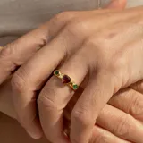 Anillo de plata 925 bañada en oro 18 K con piedra granate central en forma de corazón y una esmeralda circular a cada lado.
