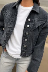 Campera de jean estilo vintage en color negro con efecto acid wash, corte clásico, cuello camisero, bolsillos superiores con solapa y cierre frontal de botones metálicos.
