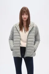 Campera acolchada tipo puffer, color beige claro, con capucha y cierre frontal. Presenta costuras horizontales y un calce entallado.