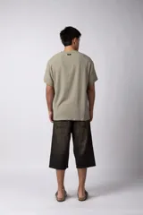 Remera de corte regular confeccionada en una mezcla de rayón y lino con textura entramada. Presenta cuello redondo, mangas cortas y un diseño de inspiración rústica y liviana.