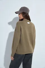 Sweater de punto gris con cuello a la base y diseño de trama geométrica en relieve. Presenta un calce relajado con mangas largas y puños tejidos.