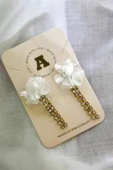 Aros colgantes con forma de flor blanca y cadena de strass dorados.