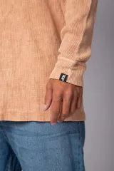 Buzo de corte oversize confeccionado en tela waffle de algodón con proceso de teñido acid wash. Presenta cuello redondo con detalle de costura en X y mangas largas con puños acanalados.