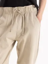Pantalón de gabardina color bordó, de tiro medio con cintura elastizada y cordón regulable. Presenta calce relajado, corte recto y largo hasta los tobillos, con bolsillos laterales.