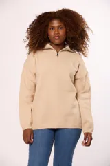 Buzo tejido de punto en color beige, con cuello alto y cierre frontal parcial, de manga larga y calce holgado.