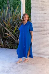 Vestido camisero de muselina color negro, de largo midi, con cuello clásico, manga corta y cierre frontal con botones.