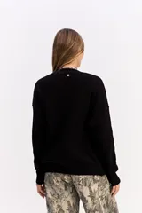 Saco de punto color crema con escote en V, cierre frontal con botones y bolsillos delanteros. Presenta un diseño de calce relajado con estructura marcada.