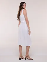 Vestido midi abotonado verde melange, con escote recto, tirantes anchos y falda de calce recto con vuelo sutil. Tiene abotonadura frontal completa con botones estilo carey, cinto textil con hebilla para ajustar la cintura y bolsillos laterales.