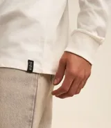 Remera de manga larga con cuello redondo, confeccionada en algodón. Presenta un corte comfort holgado y una pequeña etiqueta decorativa en el bajo.