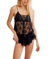 Conjunto de ropa de descanso de dos piezas, color negro, compuesto por un camisola con tirantes finos y un short. Ambas piezas son de encaje floral transparente y tienen detalles de ribete festoneado.